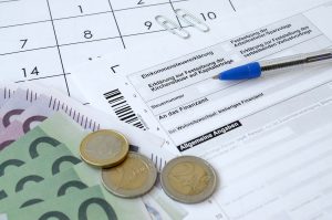 Widok na niemiecki formularz podatkowy, kalendarz i eurobanknoty – ilustracja dotycząca rozliczenia podatku i zastosowania kwoty wolnej od podatku w Niemczech w 2025 roku.